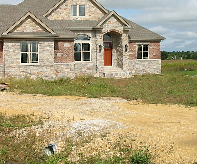 a brick house with a gray roof and a red door
