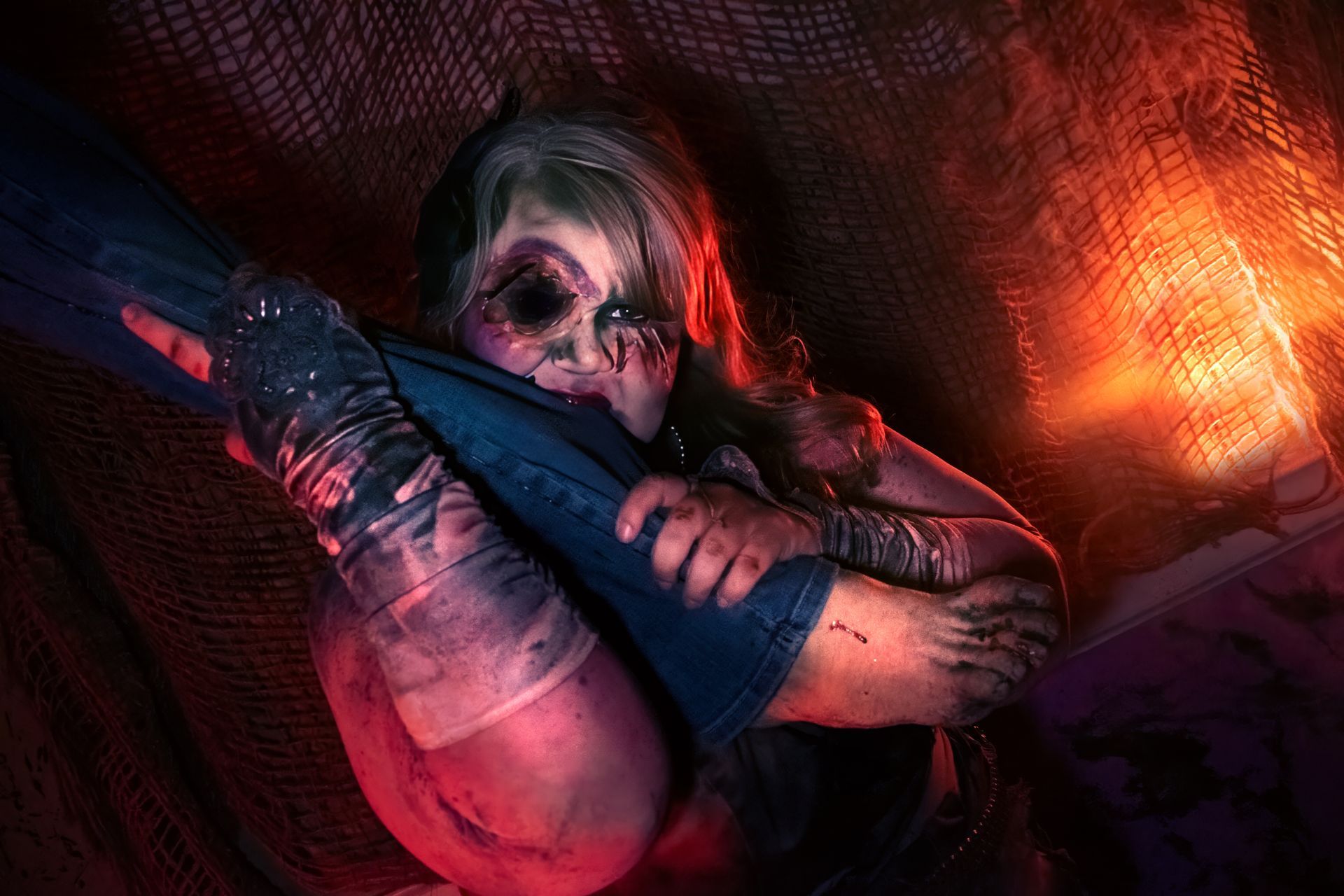 Masked person in dark lighting, biting into leg