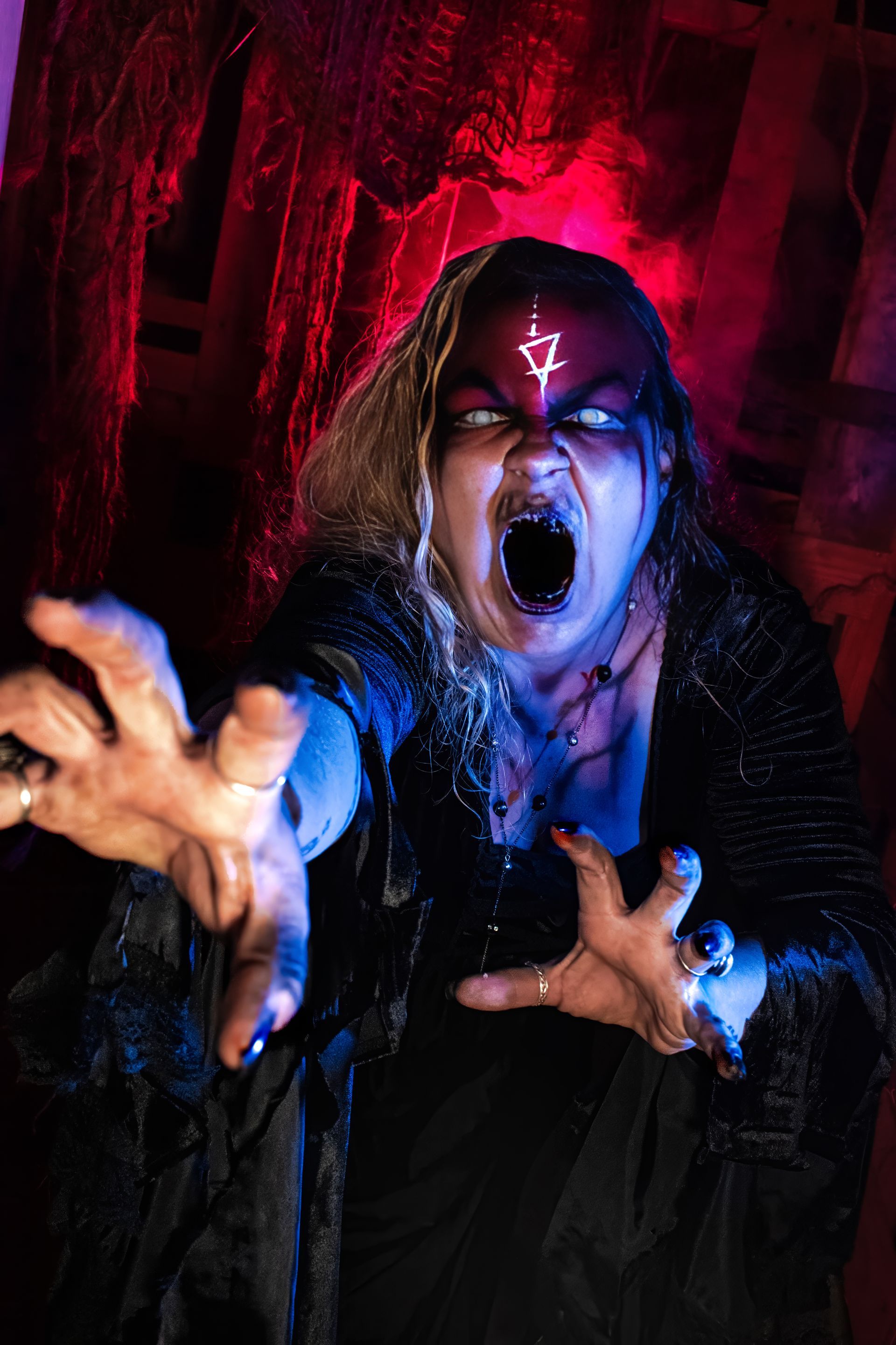 Red-lit figure with glowing eyes reaches forward, mouth open in a dark, dramatic scene