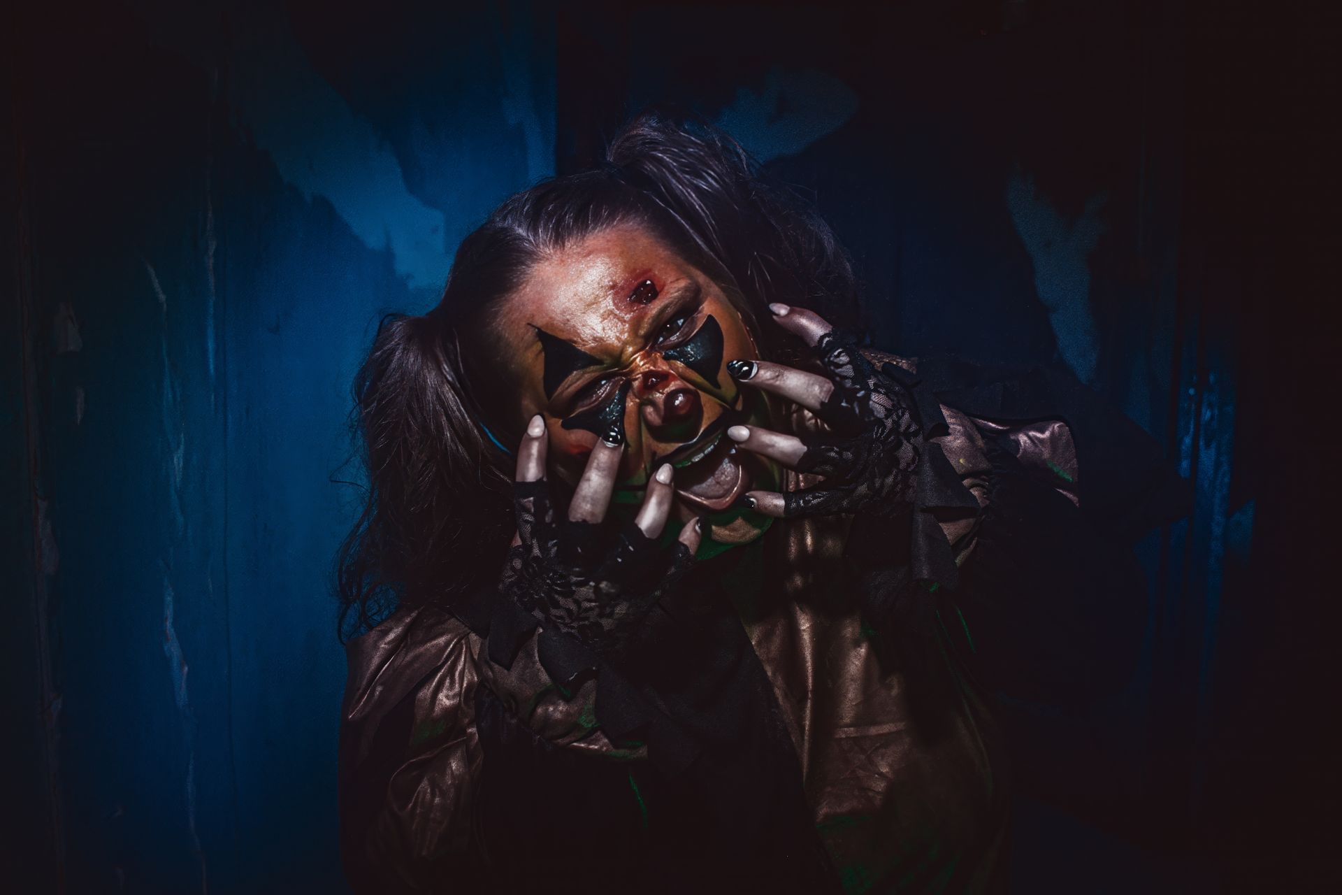 Person covering face with hands, surrounded by dark blue shadows and dramatic low light