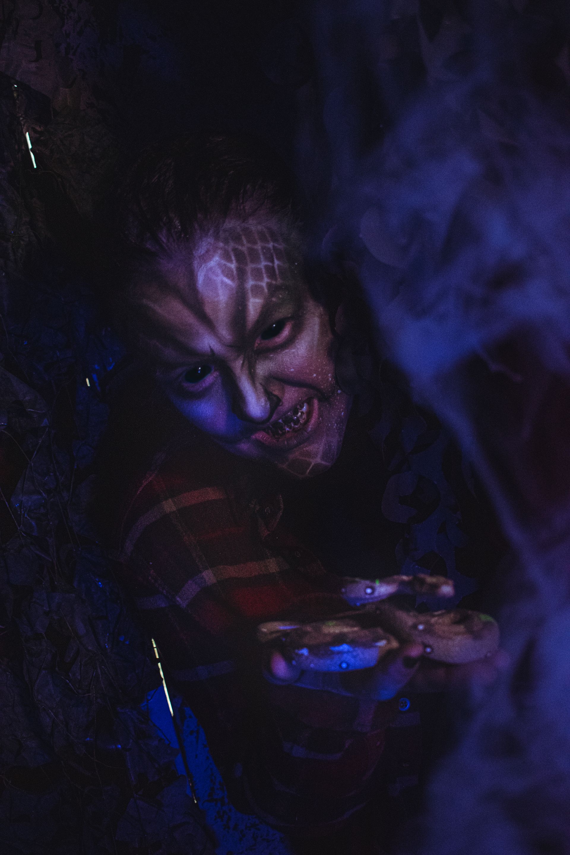 Dark, eerie portrait of a sinister face with blue-purple smoke swirling around it