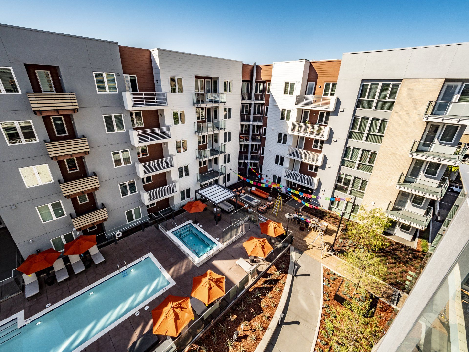 An aerial view of a large apartment building with a swimming pool and umbrellas at Capitol Towers.