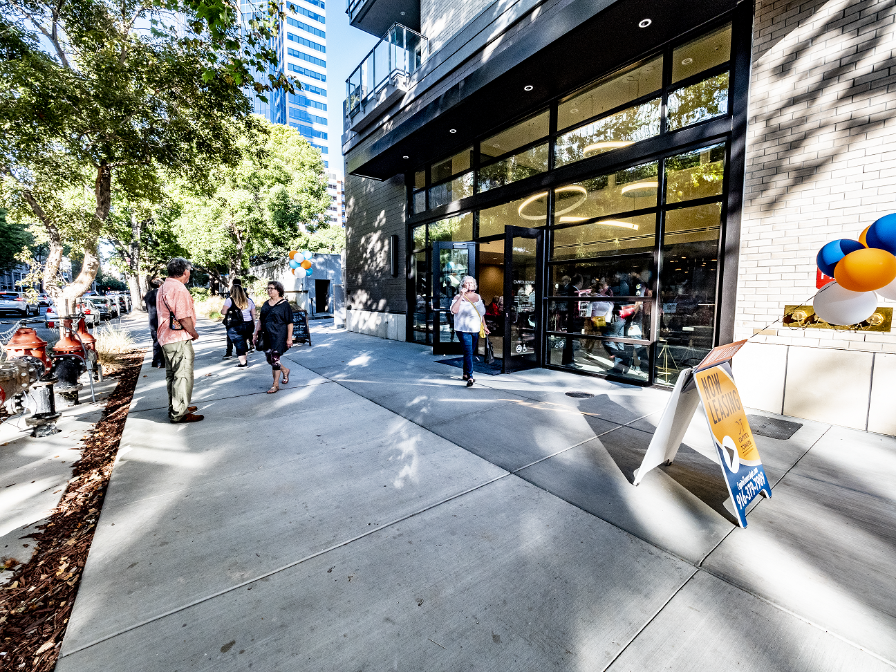 A group of people are walking down a sidewalk in front of a building at Capitol Towers.