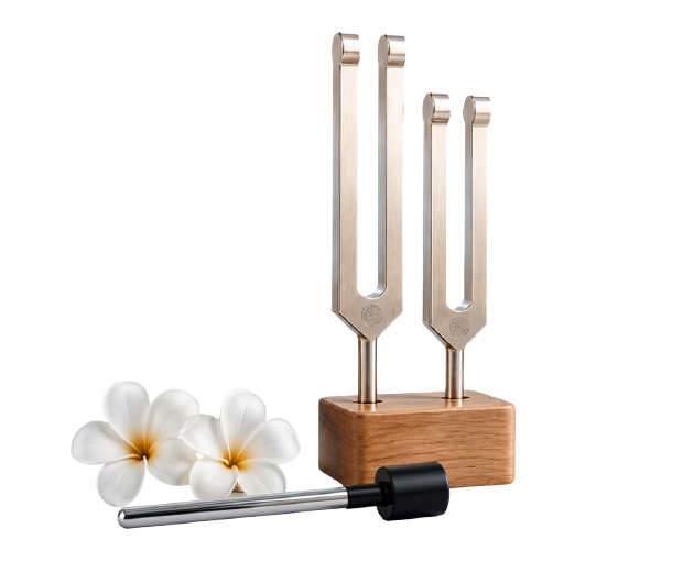 Two silver tuning forks on a wooden base beside a mallet and white flowers