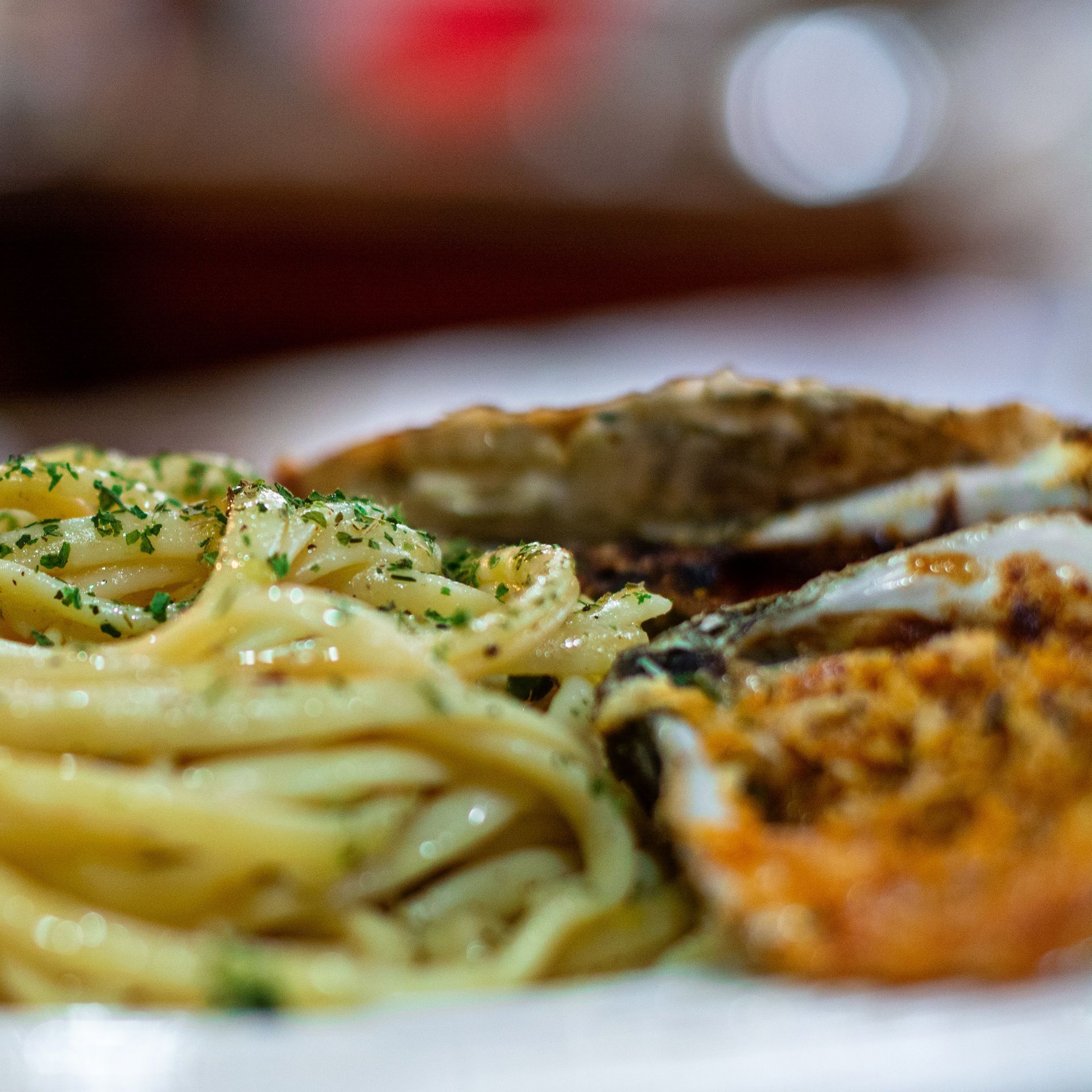 Pasta and stuffed crab on a white plate, close-up with parsley garnish.