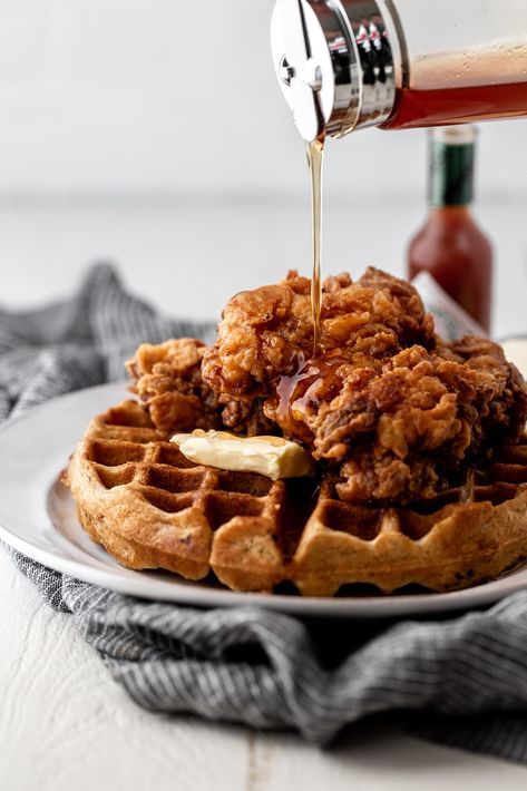 Chicken and waffles with syrup being poured over it.