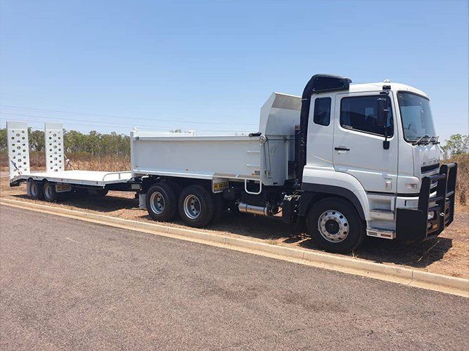 A White Dump Truck With a Trailer Attached to It is Parked on the Side of the Road — Roll Press NT In Tivendale, NT