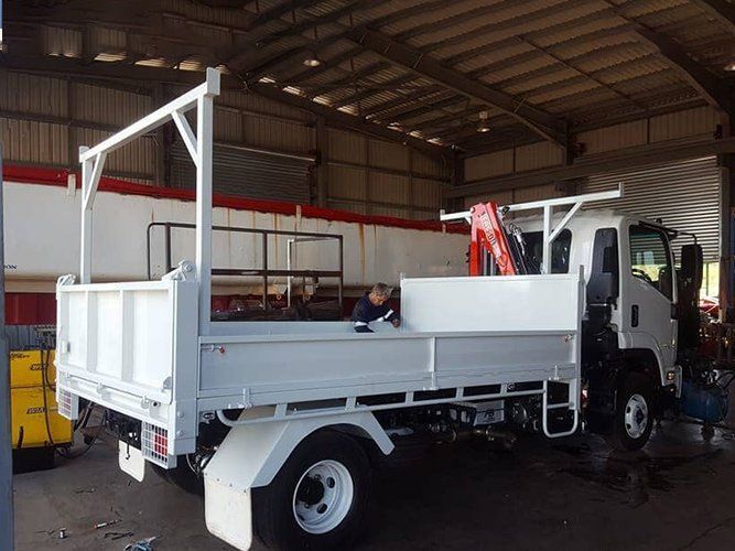 A White Truck With a Crane on the Back is Parked in a Garage — Roll Press NT In Tivendale, NT