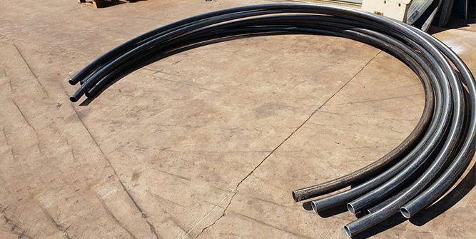 A Bunch of Black Pipes Are Stacked on Top of Each Other on the Ground — Roll Press NT In Tivendale, NT