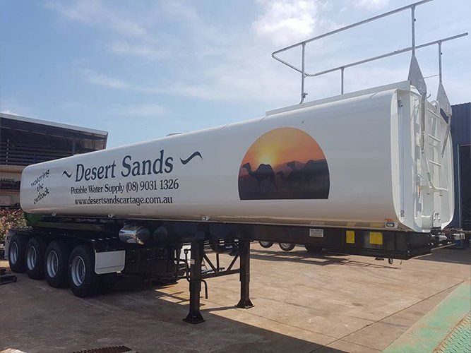A White Trailer With the Words Desert Sands Written on It is Parked in a Parking Lot — Roll Press NT In Tivendale, NT