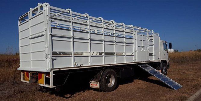 A White Truck With a Ramp on the Back is Parked in a Field — Roll Press NT In Tivendale, NT