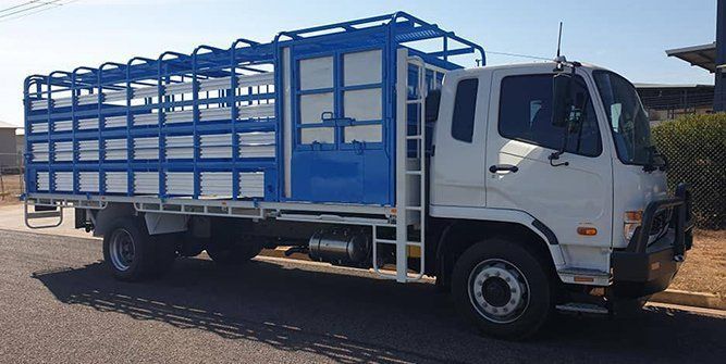 A White Truck With a Blue Cage on the Back is Parked on the Side of the Road — Roll Press NT In Tivendale, NT
