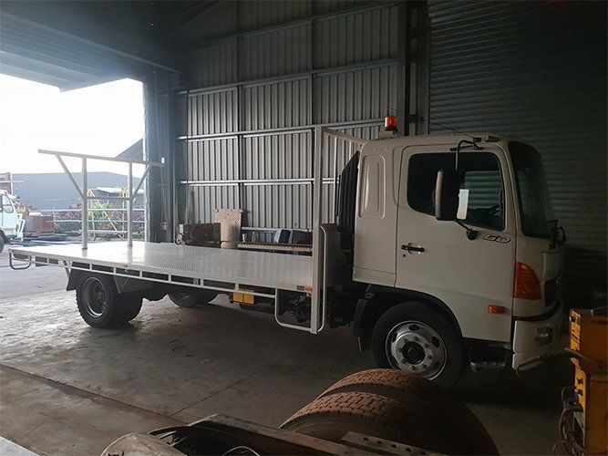 A White Flatbed Truck is Parked in a Garage — Roll Press NT In Tivendale, NT