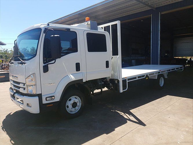 A White Truck With a Flat Bed is Parked in Front of a Building — Roll Press NT In Tivendale, NT