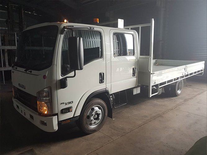 A White Truck With a Flat Bed is Parked in a Dark Warehouse — Roll Press NT In Tivendale, NT