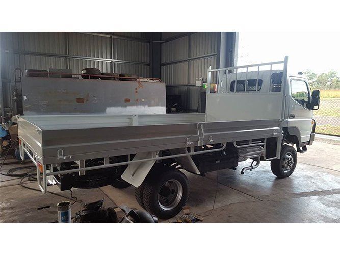 A White Truck With a Flat Bed is Parked in a Garage — Roll Press NT In Tivendale, NT