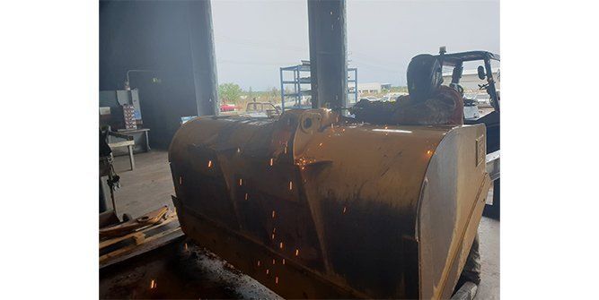 A Man is Cutting a Piece of Metal in a Garage — Roll Press NT In Tivendale, NT