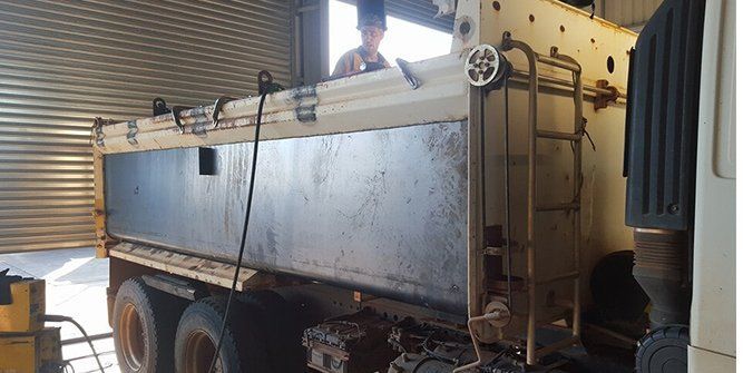 A Man is Sitting in the Driver's Seat of a Dump Truck — Roll Press NT In Tivendale, NT