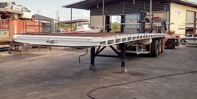 A Flatbed Trailer is Parked in a Parking Lot in Front of a Building — Roll Press NT In Tivendale, NT