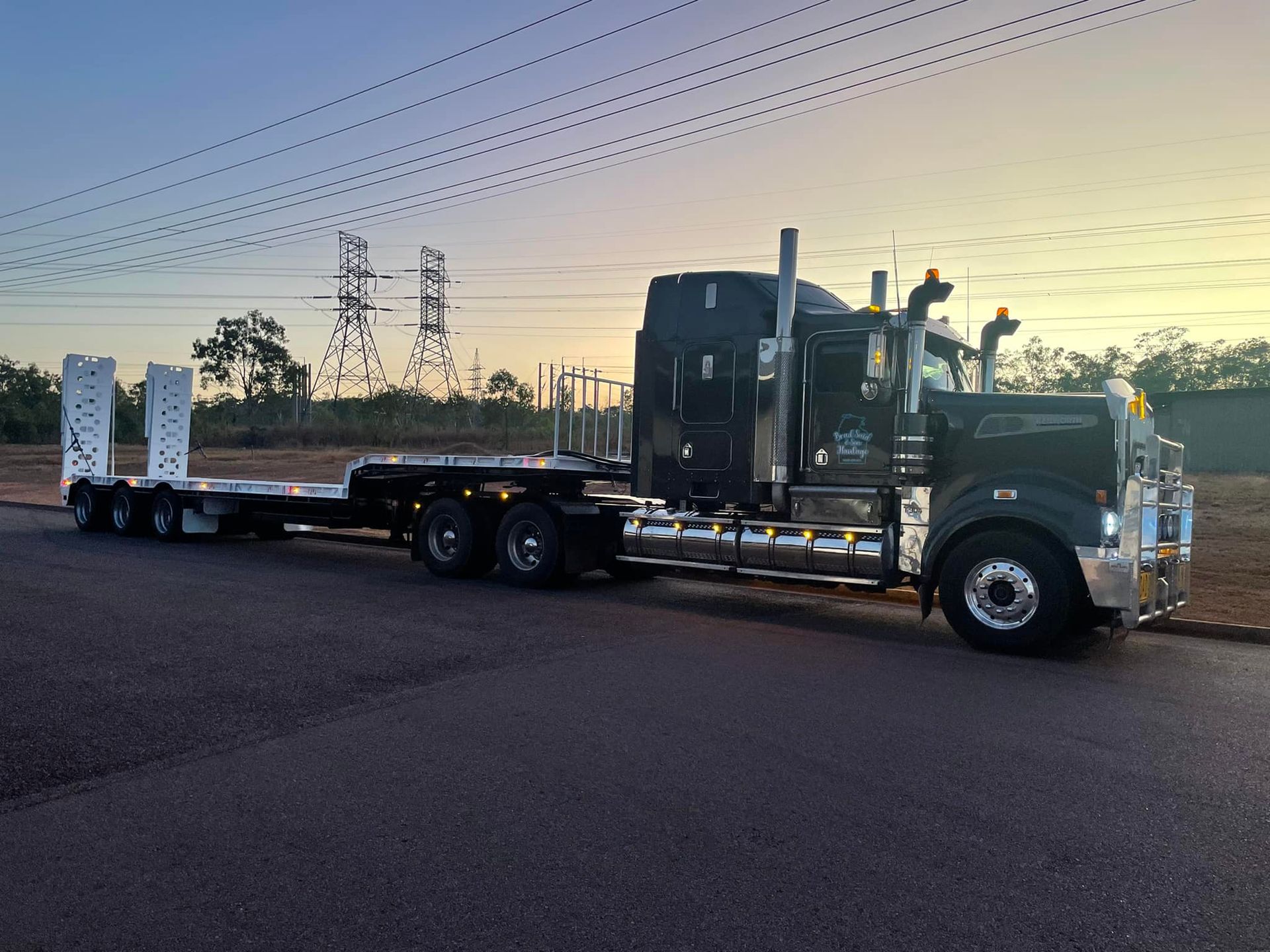 A Semi Truck With a Flatbed Trailer is Parked on the Side of the Road — Roll Press NT In Katherine, NT