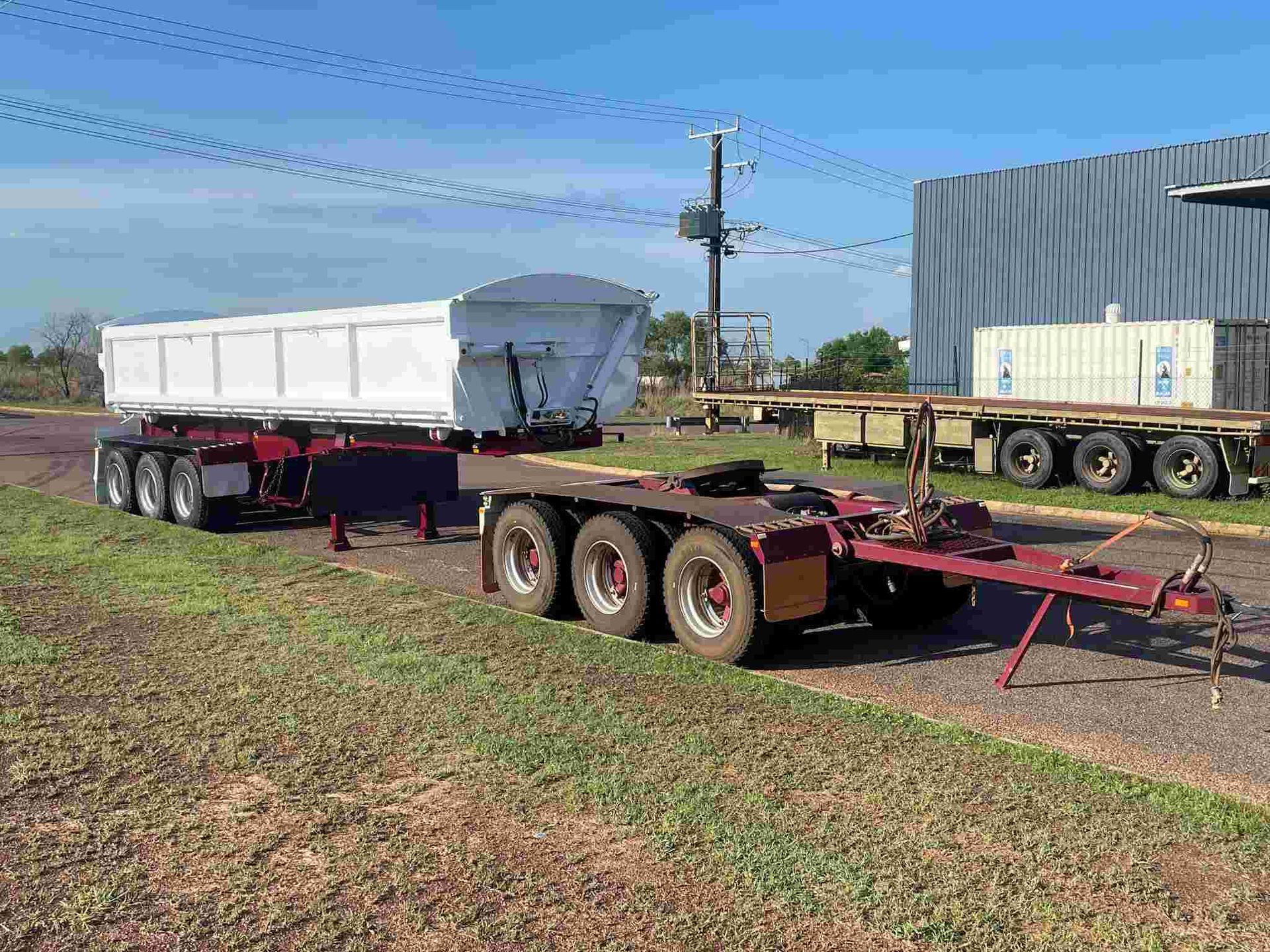 A Trailer is Parked in a Grassy Field Next to a Building — Roll Press NT In Tivendale, NT