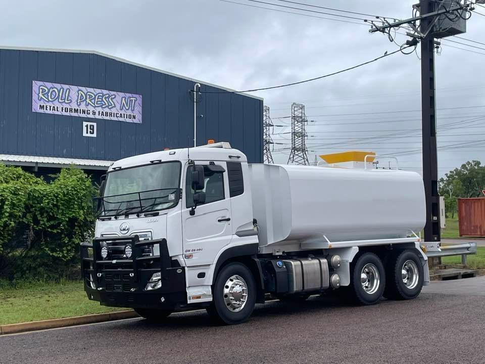 A White Tanker Truck is Parked on the Side of the Road in Front of a Building — Roll Press NT In Tivendale, NT