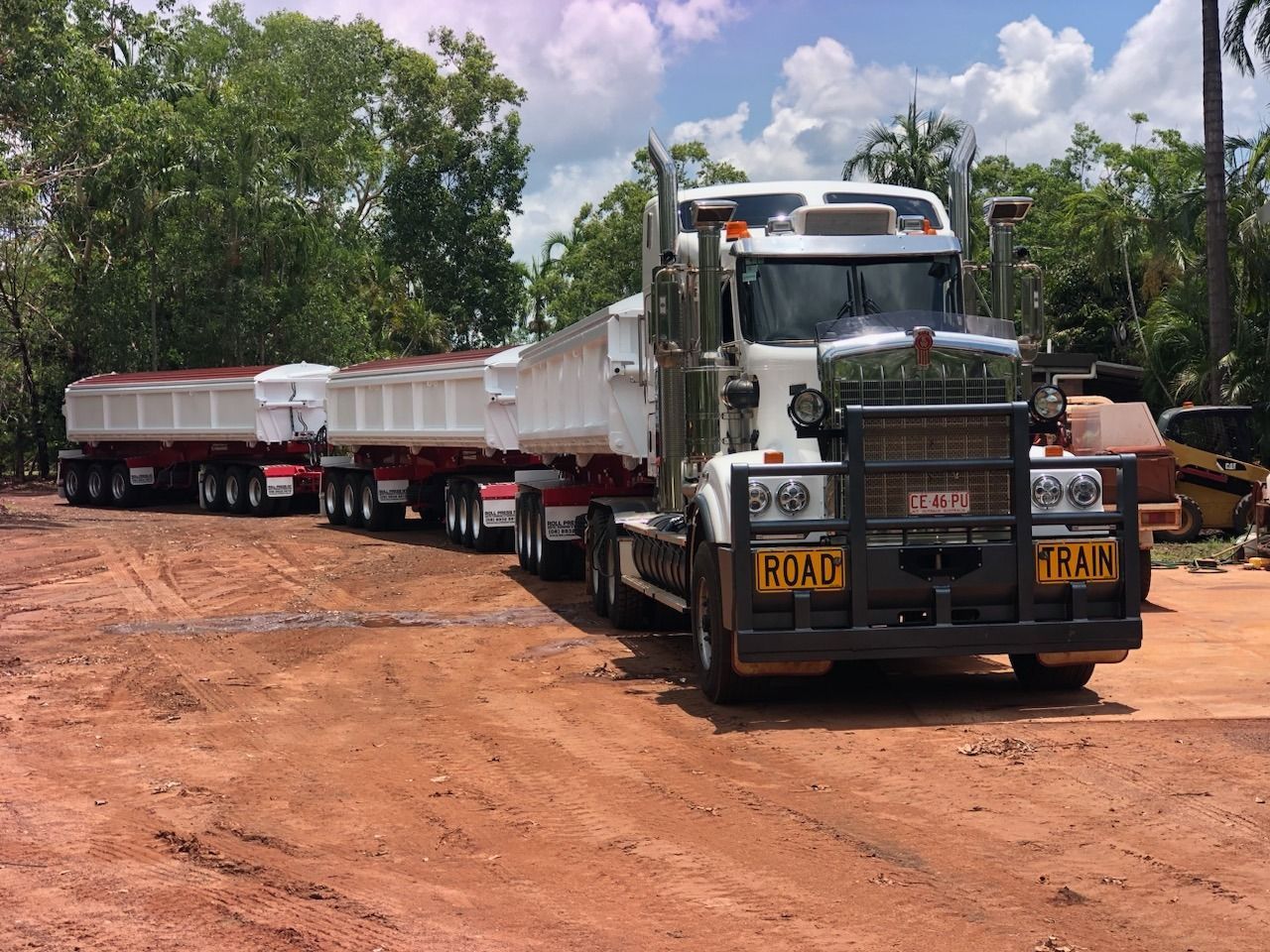 A Dump Truck With a Trailer Attached to It is Parked in a Dirt Lot — Roll Press NT In Alice Springs, NT