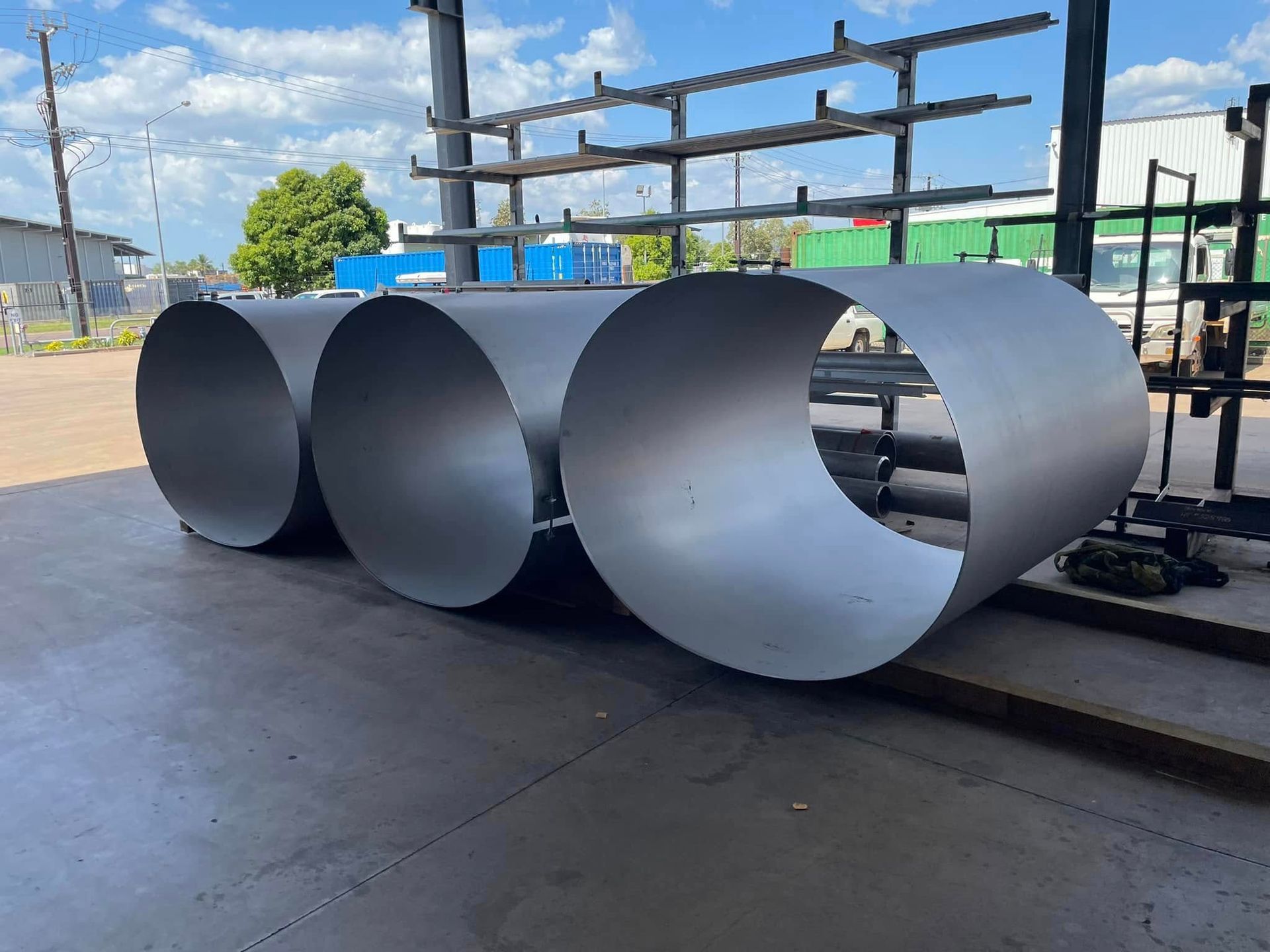 Three Stainless Steel Pipes Are Stacked on Top of Each Other on the Ground — Roll Press NT In Tivendale, NT