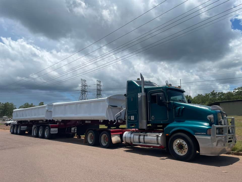 A Green Semi Truck With a White Trailer is Parked on the Side of the Road — Roll Press NT In Tivendale, NT