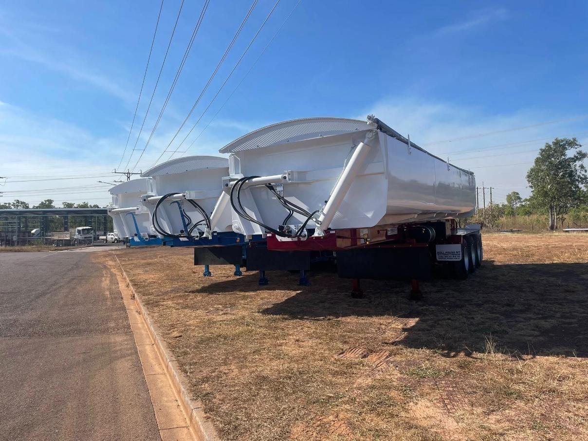 Two White Dump Trailers Parked On Dry Grass Under A Blue Sky With Power Lines — Roll Press NT In Tivendale, NT