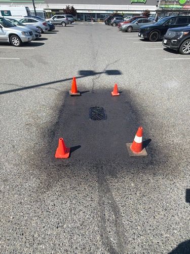 Parking lot with four orange traffic cones marking a dark stain on the pavement