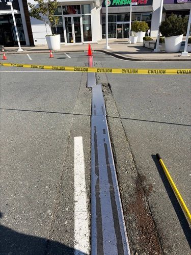 Curb ramp at storefront entrance blocked off with yellow caution tape and orange cones.