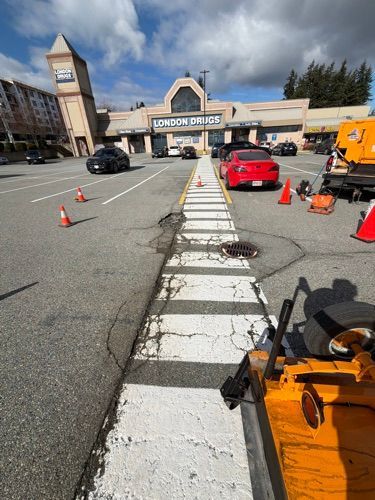 Parking lot lane with traffic cones and orange equipment in front of a building under repair