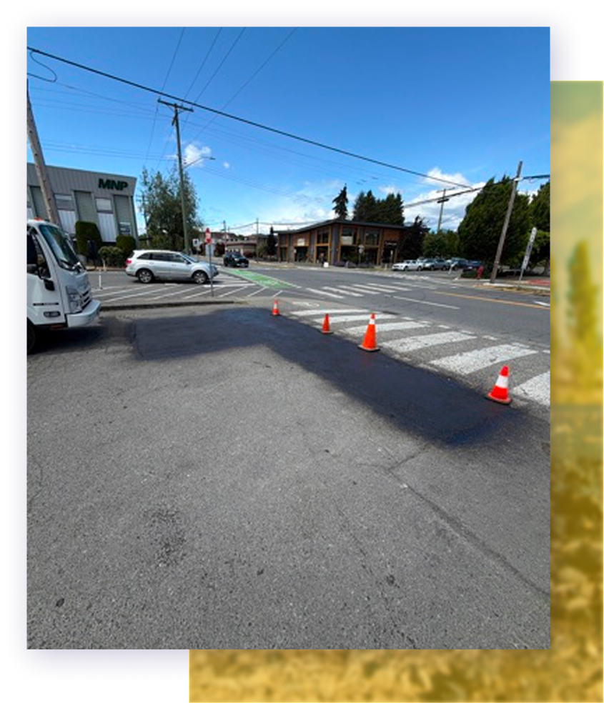 Street view of an intersection with orange cones blocking part of the road under a blue sky