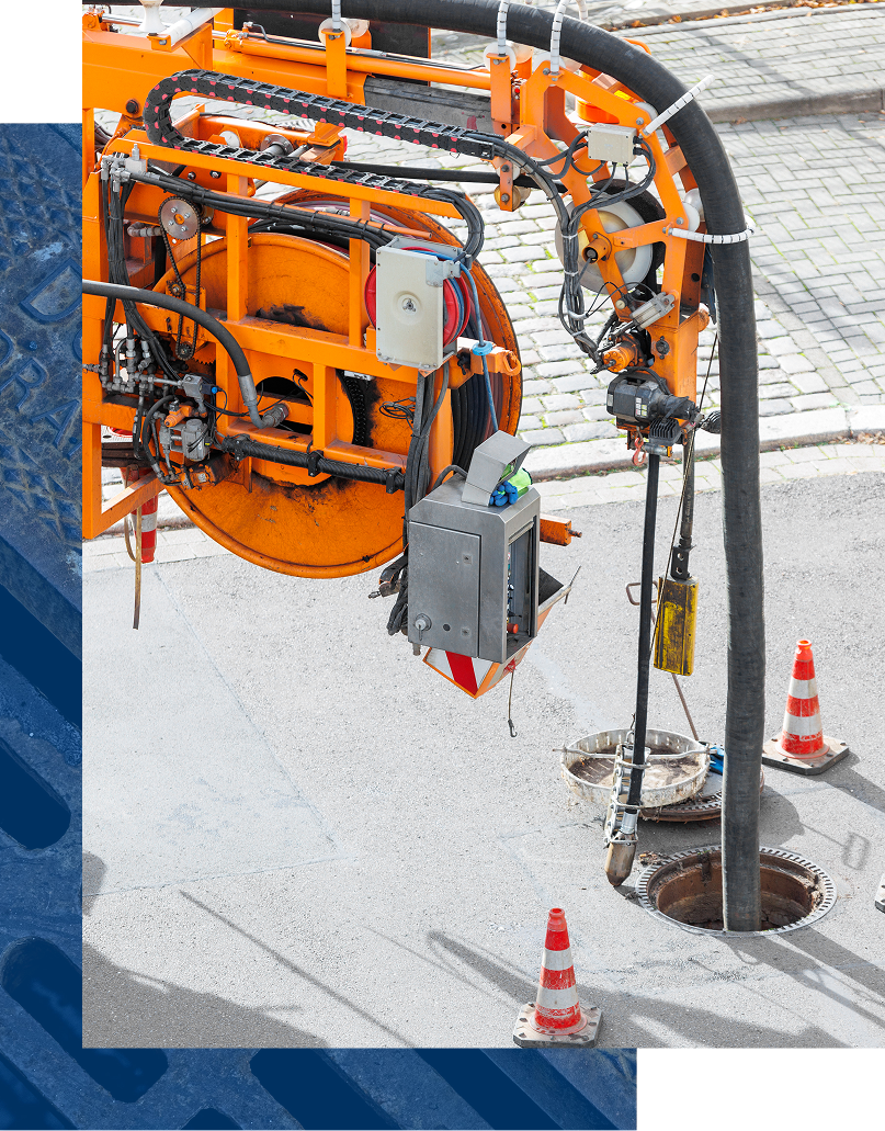 Orange industrial machine on a snowy construction site near a utility pole and traffic cones