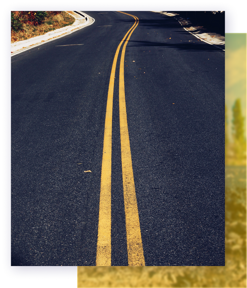 Double yellow lines on an asphalt road curving into the distance.