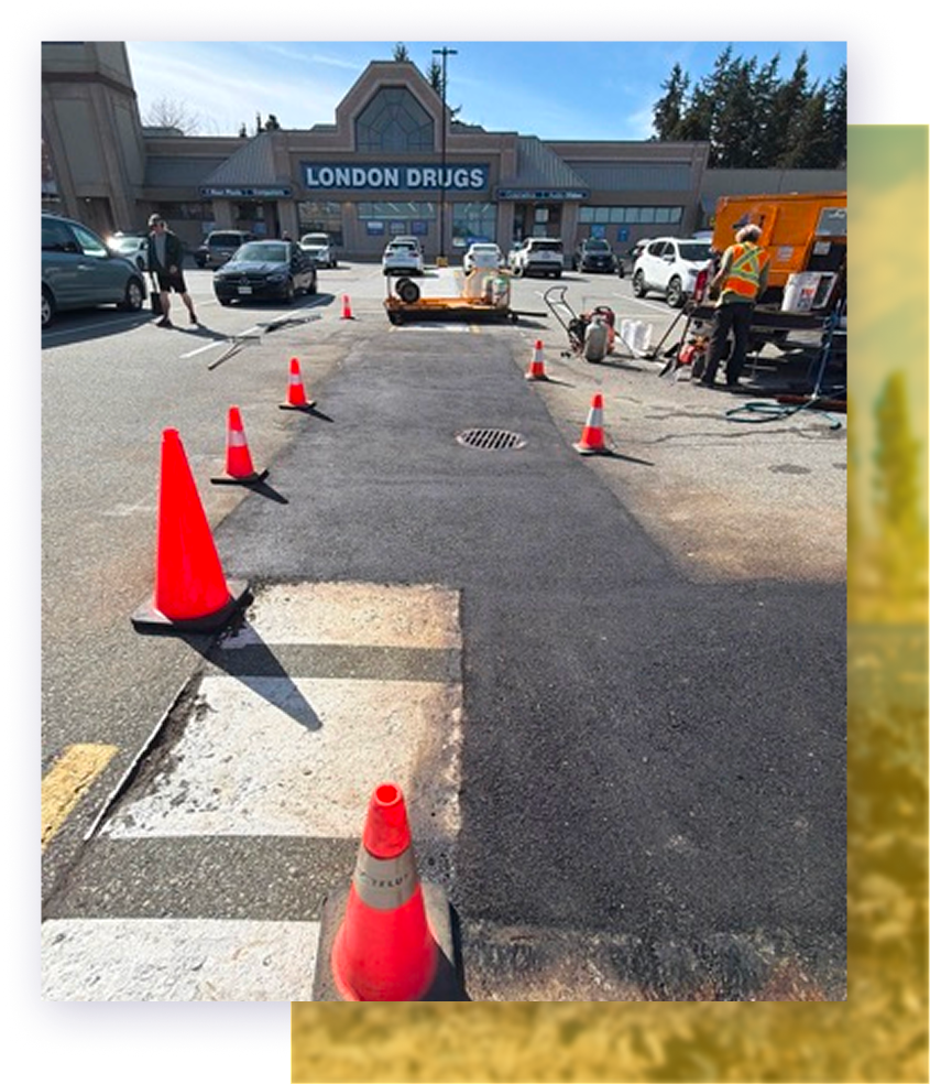 Coned-off parking lot work area in front of London Drugs store, with traffic cones and equipment.