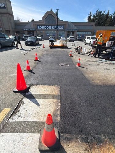 Roadwork cones blocking a parking lot lane outside a London Drugs store