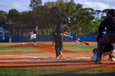 Baseball player sliding into home plate, catcher in front. Blue and gold uniforms, action shot.
