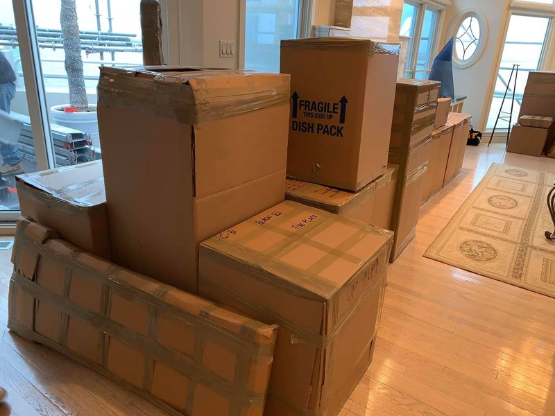 A bunch of cardboard boxes are stacked on top of each other in a living room.