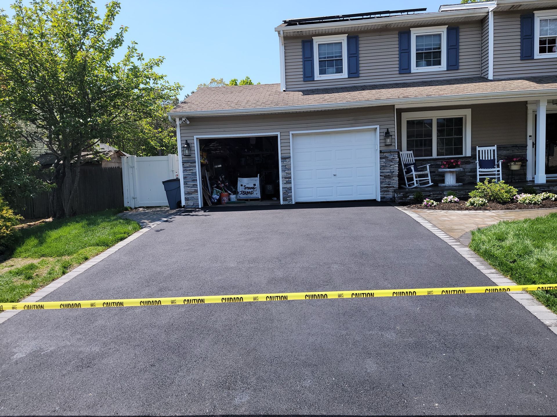 A house with two garage doors is surrounded by a yellow tape.