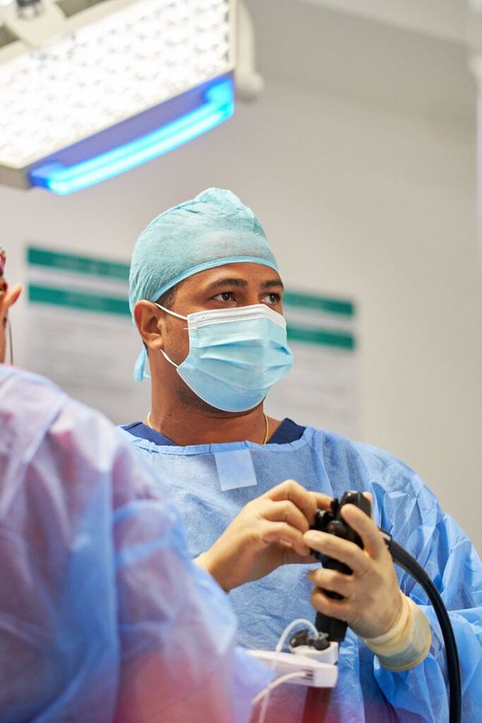 A surgeon wearing a mask and gown is holding an endoscope in an operating room.