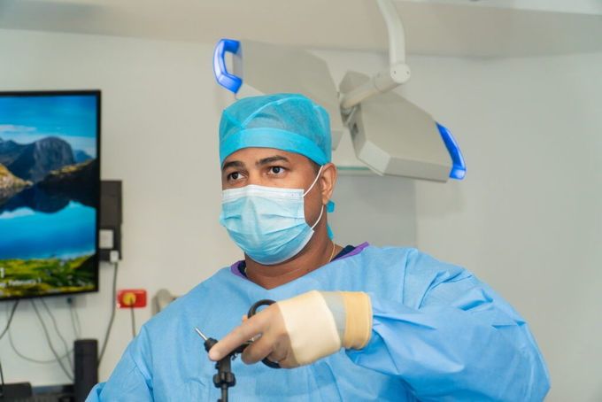 A surgeon wearing a mask and gown is holding a surgical instrument in an operating room.