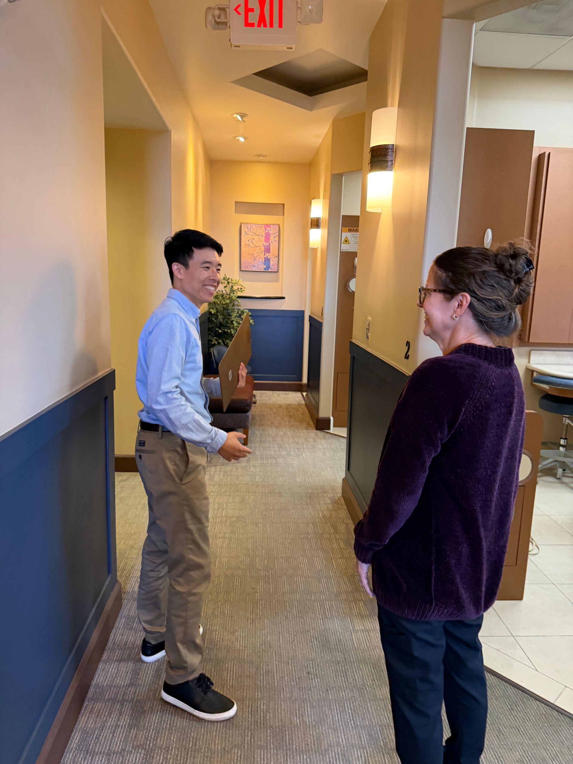 Reception desk conversation with a man handing papers to a staff member in a clinic or office