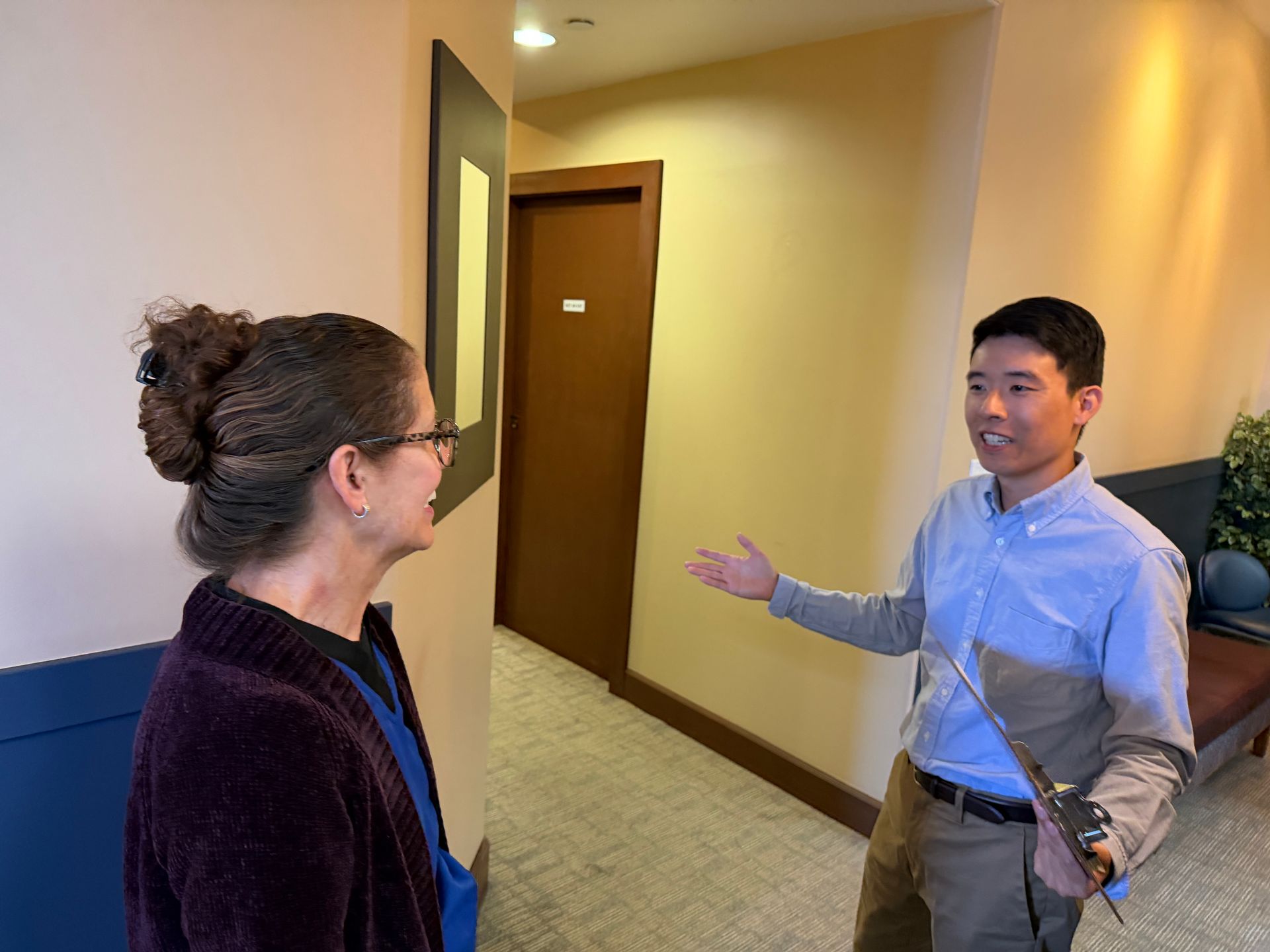 Patient at clinic reception handing paperwork to a smiling staff member behind the desk