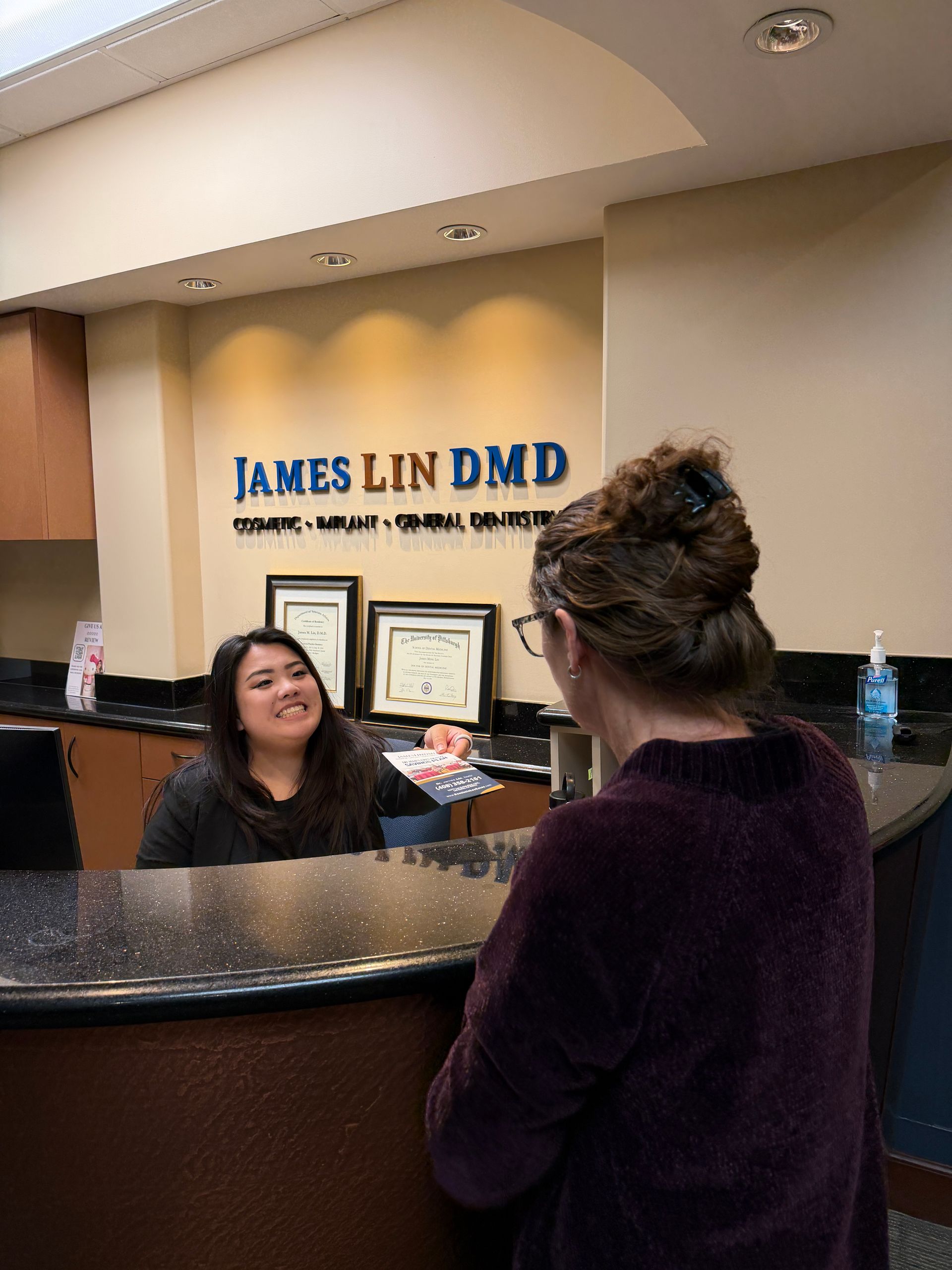 Dentist speaking with a smiling patient in a dental exam room