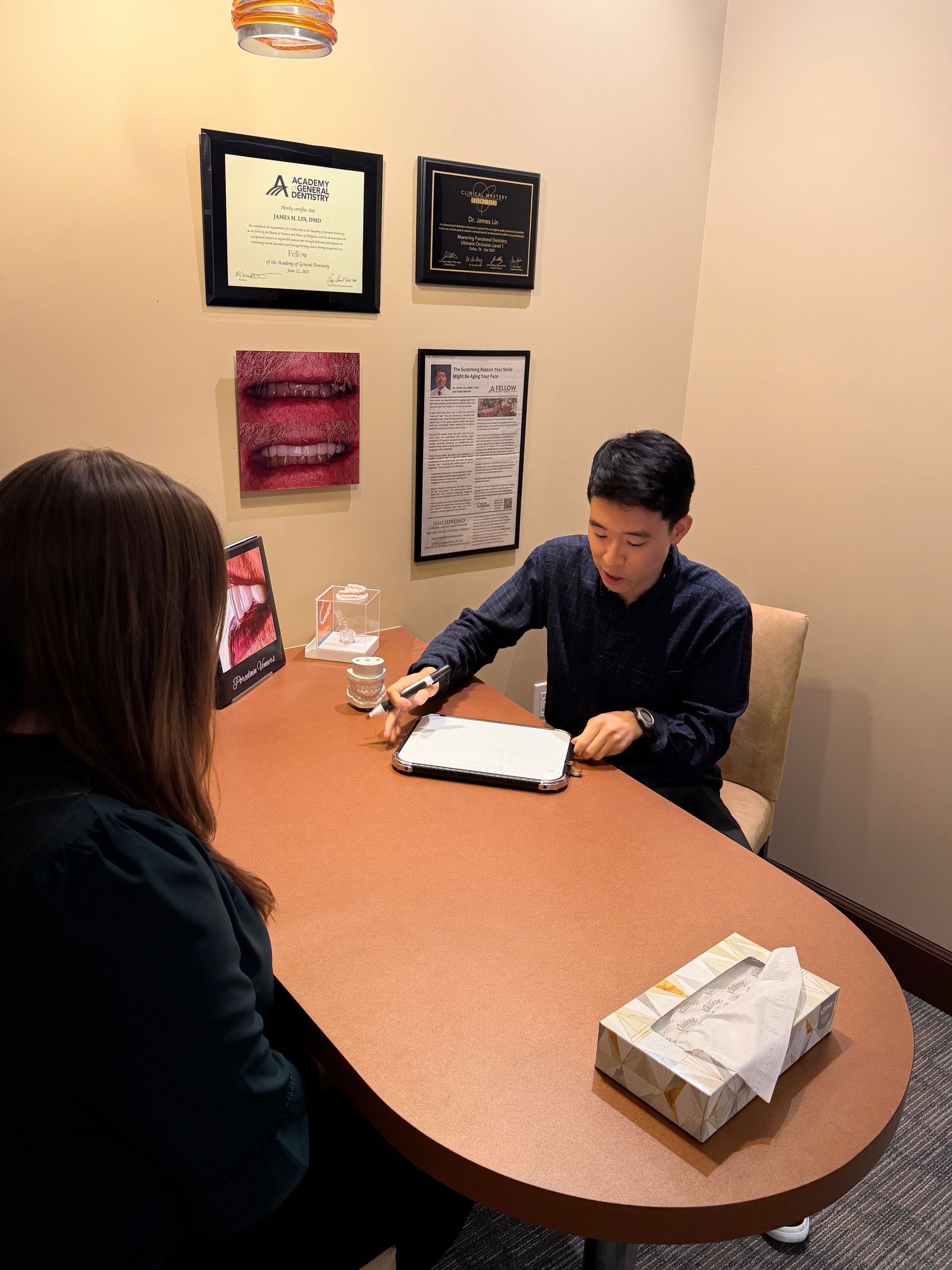 Two people reviewing a 3D dental model with a computer monitor in a clinic office