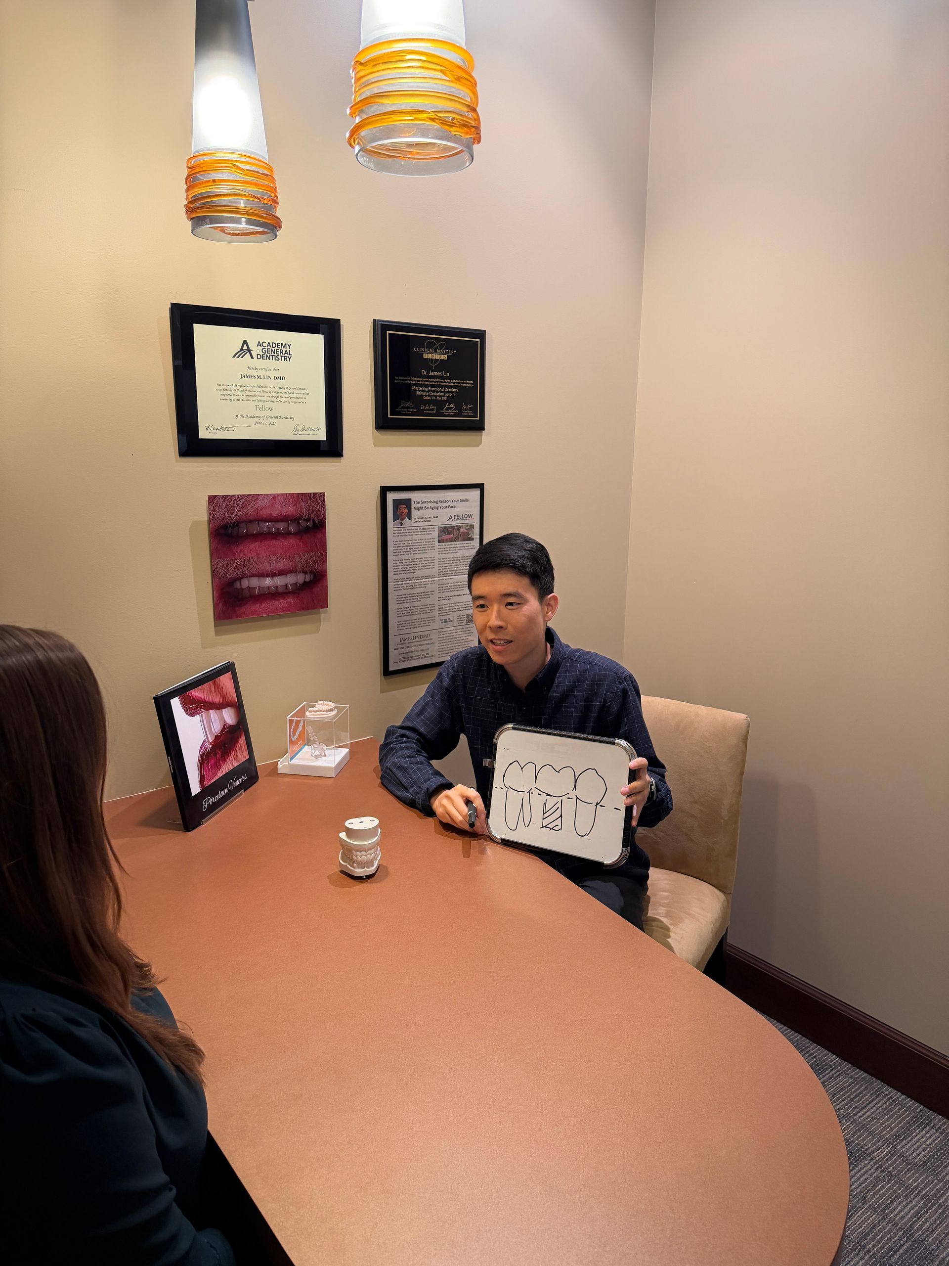 Dentist reviewing dental X-rays on a desktop monitor, seated at a white workstation with gloved hands.
