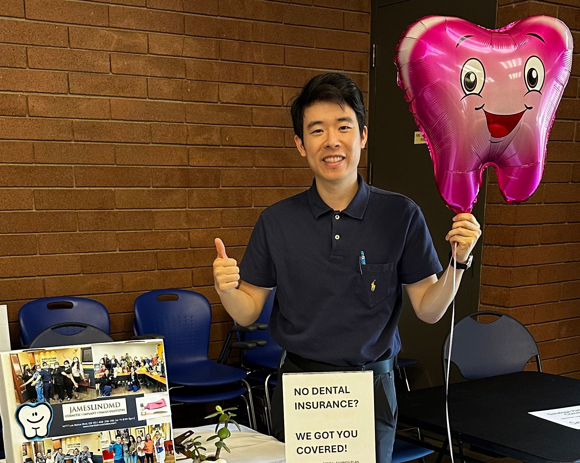 Man at a Jamesline booth smiling and holding a pink heart balloon at an indoor event