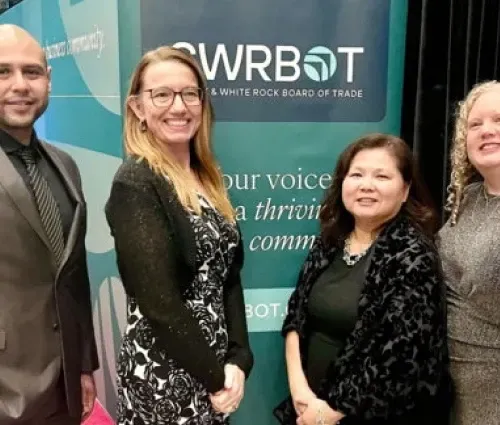 Four people posing in front of a WRT booth banner at a trade show